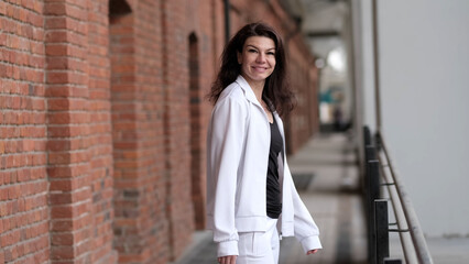 A woman in a casual white jacket stands with arms crossed, exuding a calm and approachable demeanor. This photo highlights the importance of taking moments to reflect and appreciate personal growth.