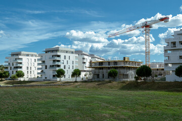 un quartier tout neuf avec des immeubles , dont un en construction avec une grue et des espaces verts