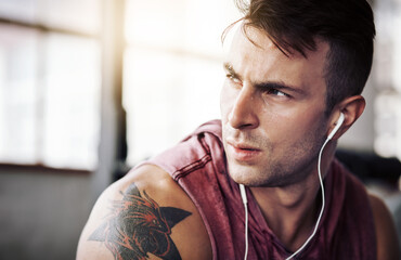Man, tired and music in gym for fitness, exercise and wellness with radio for motivation. Training, thinking and male bodybuilder on break from cardio, workout or earphones for listening to podcast