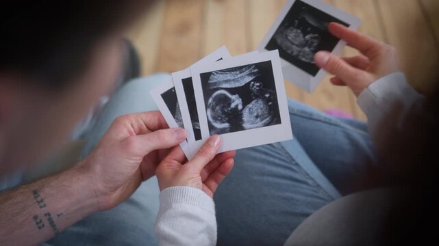 Unrecognizable pregnant couple pregnancy medical insurance health parents at clinic at home man guy male father woman girl female mother holding usd ultrasound examination photo images future baby