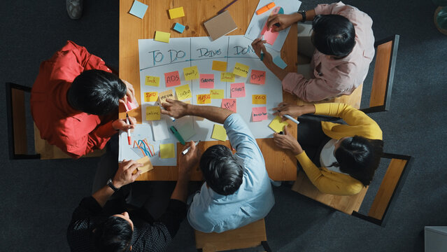 Top view of people writing and making scrum task board while writing marketing and planning strategy at colorful sticky notes. Smart team manage work performance by using kanaban board. Convocation.