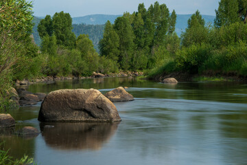 Long exposure photography with flowing river, rocks  and reflection with trees in the background, Steamboat Colorado