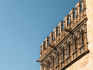 Fototapeta premium Close-up view of the Llotja de la Seda ornate Gothic architecture in Valencia, Spain, featuring intricate carvings and decorative elements against a clear blue sky.