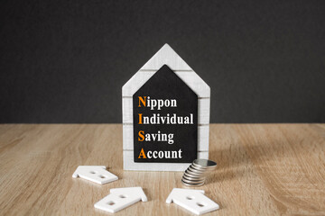 Concept words Nippon Individual Savings Account on blackboard. Beautiful wooden table, black...
