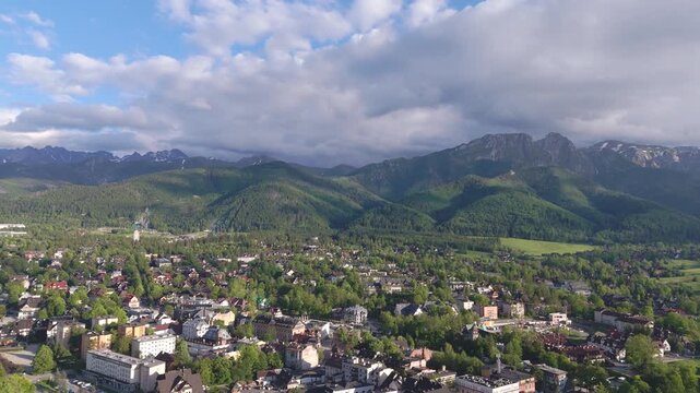 aerial flyover over the city of zakopane with panorama of mountains in spring evening in poland