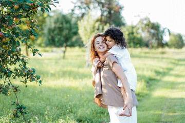 Naklejka premium Happy mother and little daughter playing outdoors. Curly redhead model in the field. Relations.