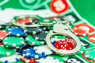 Handcuffs and a gun on a poker table - casino crime concept, underground casinos. illegal games, gambling concept. set of playing cards with dices, money and chips, on table. Casino concept, games.