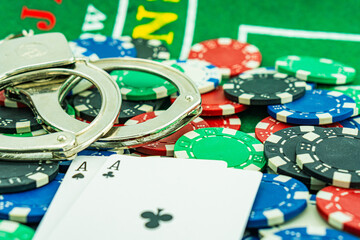 Handcuffs and a gun on a poker table - casino crime concept, underground casinos. illegal games,...