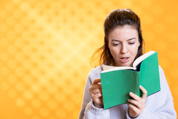 Woman shocked by interesting facts in lecture book needed for school exam, studio background. Student feeling surprised while reading compelling academic textbook needed to pass classes