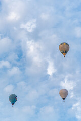 group of 3 coloured hot air balloons flying through the cloudy skies in a competition