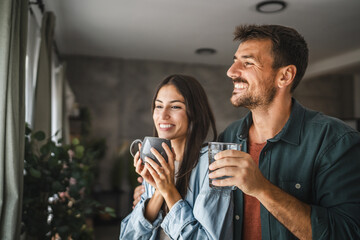 Portrait of couple stand with coffee and water, watch intro the window