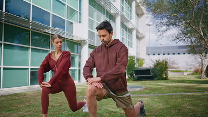 Sport friends performing lunges in morning. Man coach instructing fit woman