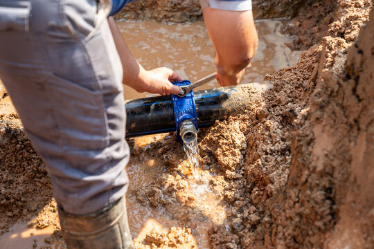 Clean water main pipe on the street, additional fitting is broken or burst and leaking water.  It is being repaired by a professional team.