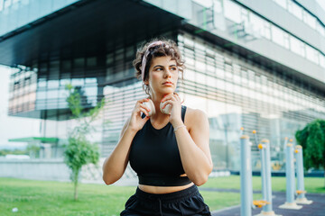 Young caucasian woman putting headphones preparing for training in park