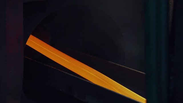 Yellow Hot Metal Striped Bars at Industrial Line of Copper Production Factory. Metal comes from the industrial oven. Furnace. Processing line at Non Ferrous Plant. Dark Background. Close Up