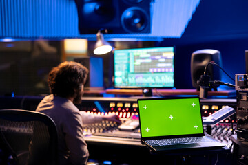 Sound engineer working on control desk with greenscreen layout in professional studio, using...
