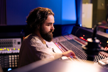 Sound producer working on mixing and mastering sounds with pc software, editing music with audio...