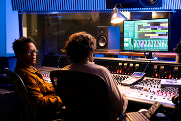 Pleased musician and tracking engineer creating a song together, mixing and mastering new songs to...