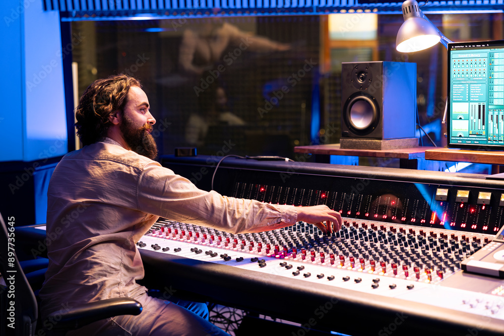 Poster Music engineer applying mix and master techniques on old recordings, pressing buttons and switchers to add audio effects in post production. Record producer creating new songs with console.