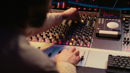 Male producer working at mixing panel in the professional recording studio, working on new hits...