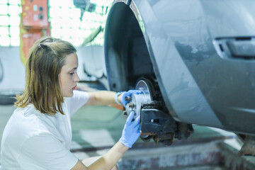 female auto mechanic repairs car brake system