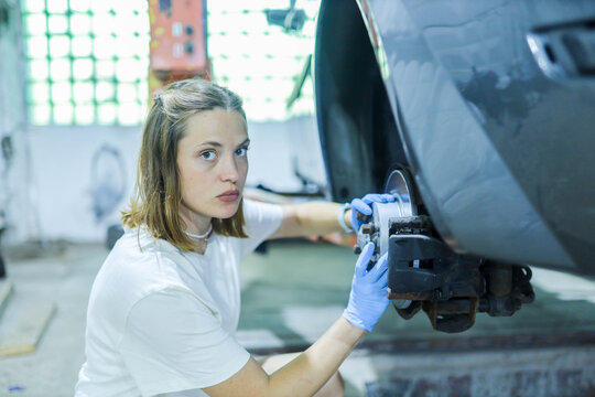 female auto mechanic repairs car brake system - Powered by Adobe