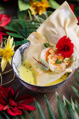 Shrimp Soup with Crispy Shell, Mango, and Edible Flowersю Refined gourmet soup with shrimp, mango cubes, and green herb sauce, served in a crispy shell and topped with edible flowers. Artistic plating