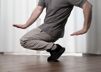Naklejka premium Dance in motion, pose of a man in hip-hop style clothes. Sports dancing guy in training poses. Dance training at home.