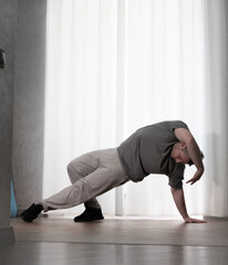 Dance in motion, pose of a man in hip-hop style clothes. Sports dancing guy in training poses. Dance training at home.