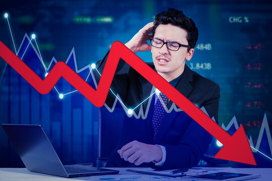 Frustrated businessman with downtrend market chart with laptop computer