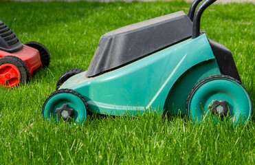 Fototapeta premium Seasonal maintenance works in garden, lawn movers in action, green grass cutting, lawn care, English lawn