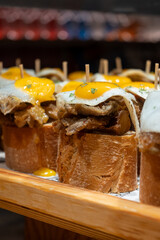 Typical snack of Basque Country, pinchos or pinxtos skewers with small pieces of bread, fish, sea food, fried eggs served in bar in San-Sebastian or Bilbao, Spain, close up