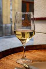 Obraz premium Glass of txakoli or chacolí slightly sparkling very dry white wine produced in Spanish Basque Country in typical pinchos bar in old part of San Sebastian or Donostia, Spain