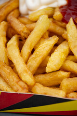 Belgian street and fast food, paper box in colors of Belgian flag with fried potato frit chips and ketchup and mayonnaise sauсe