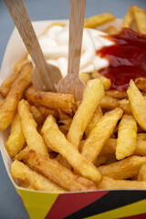 Belgian street and fast food, paper box in colors of Belgian flag with fried potato frit chips and ketchup and mayonnaise sauсe