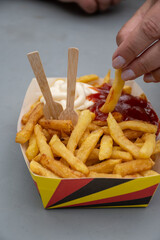 Belgian street and fast food, paper box in colors of Belgian flag with fried potato frit chips and ketchup and mayonnaise sauсe
