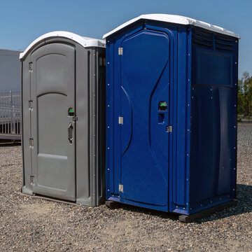 Two porta potty toilets outside near raceway.