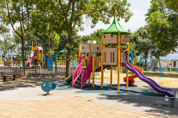 Colorful Bright Kids Playground. Fun Slide, Small Children Play Area In Green Park On Warm Day. Climbing Wall, Climbing Frames. Summer Leisure And Recreation, Games, Family Walk, Nobody. Horizontal