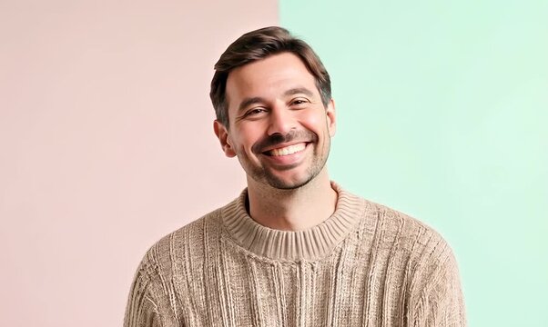Group portrait video of a grinning man in his 40s wearing a cozy sweater against a pastel or soft colors background