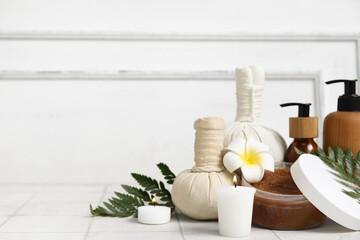 Set of spa supplies with different cosmetic products, herbal bags, fern branches, plumeria flower...