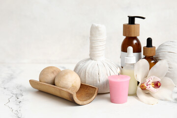 Set of spa supplies with different cosmetic products, herbal bags, orchid flower and burning...