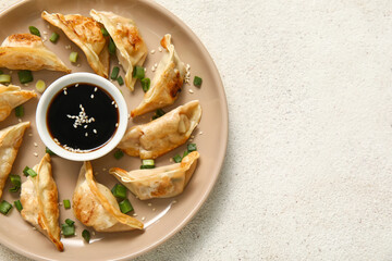 Plate with fried Japanese gyoza and bowl of soy sauce on white background