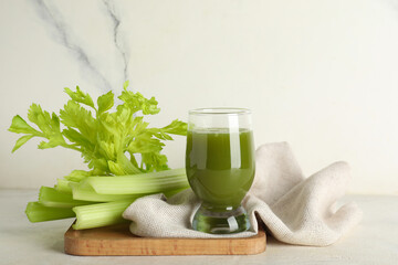 Glass of healthy celery juice on white table