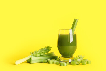 Glass of celery juice with whole and chopped celery on yellow background