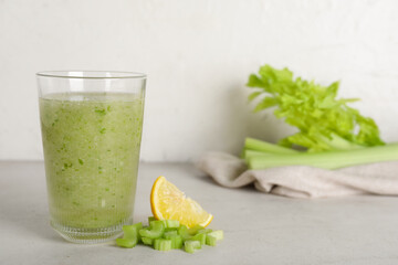 Glass of celery juice and lemon on white background