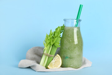 Bottle of celery juice with celery and lemon on blue background