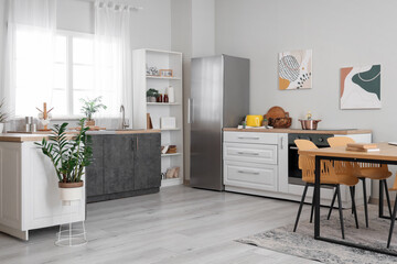 Dining table in interior of kitchen with fridge and counter