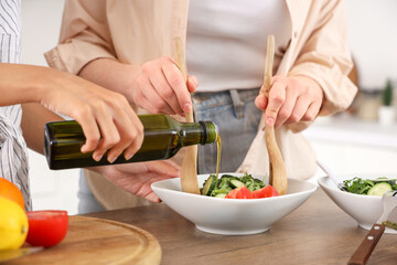Young women making salad in kitchen, closeup