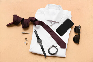 Set of male accessories with white shirt, tie and mobile phone on beige background. Top view