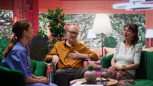 Nurse jumping to help senior man in wheelchair losing conscience during home visit, old person hyperventilating and scaring his wife. Medical assistant in panic checking the pulse. Camera B.